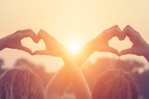 two people holding hands air in heart shapes